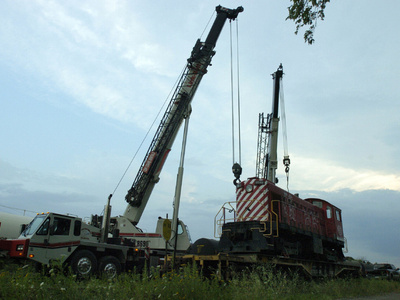 prepare to lift a locomotive from a flat car in Kitchener on Tuesday evening. The 1957 locomotive was acquired by the Southern Ontario Locomotive Restoration Society, which operates the Waterloo Central Railway.